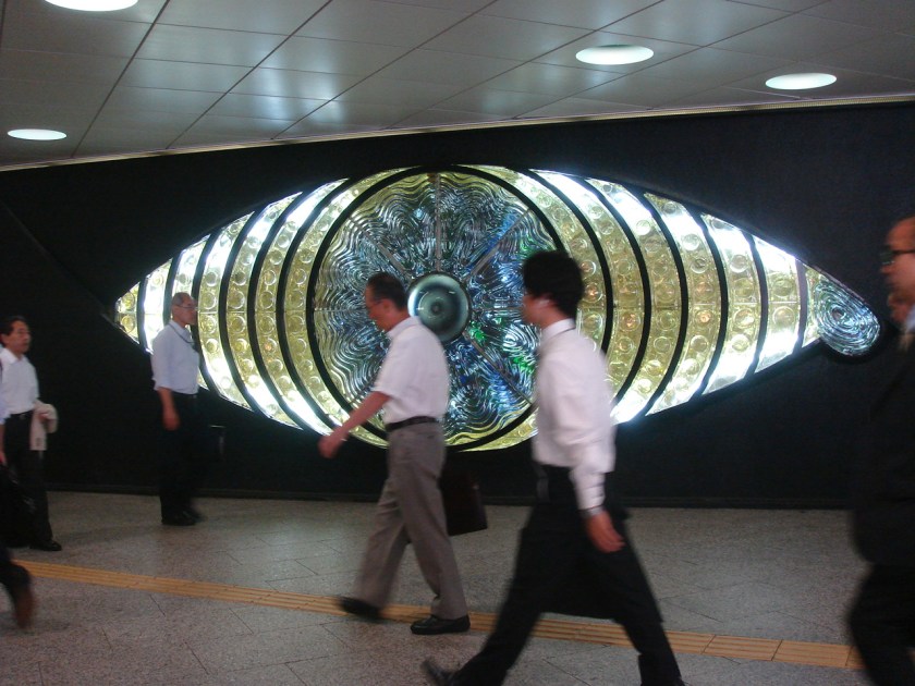Somebody's watching you... office workers walk past an installation in Shinjuku station, Tokyo